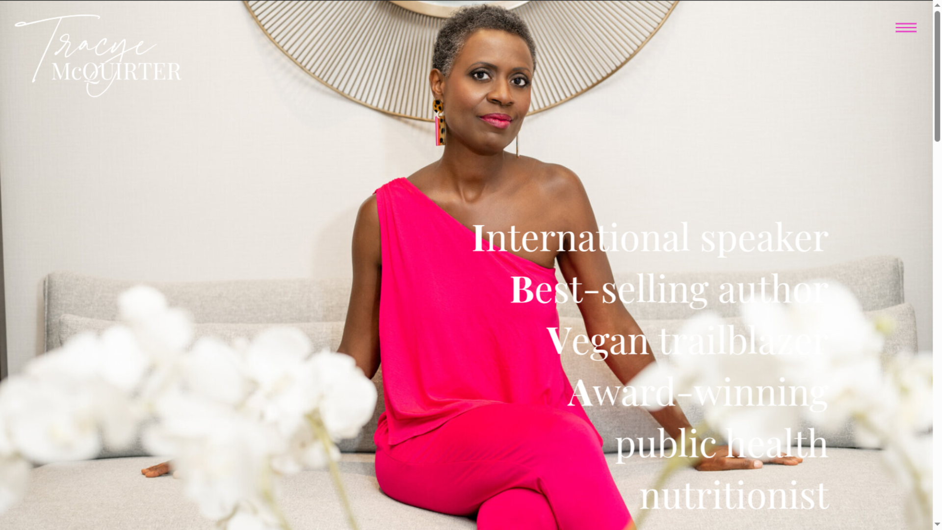 Portrait of Tracy McQuirter, international speaker and vegan nutrition advocate, seated on a couch wearing a bright pink dress, featured on a personal branding website highlighting her work as a best selling author and public health nutritionist 